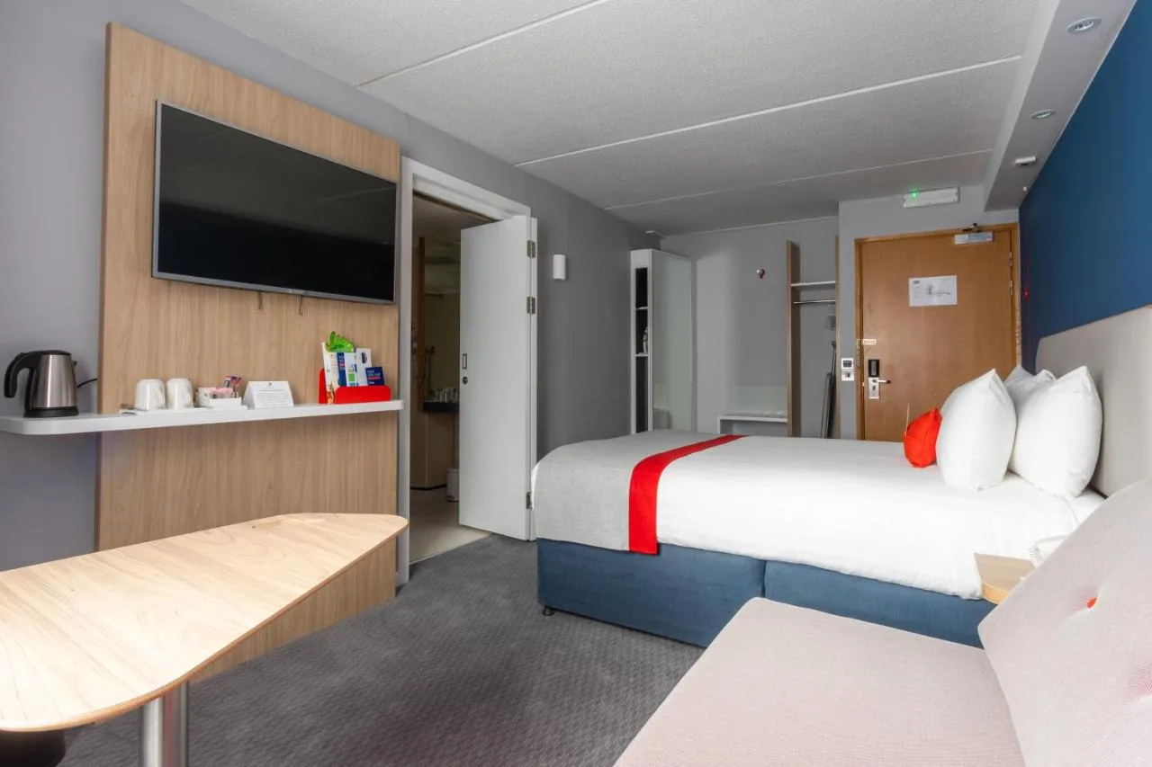 a hotel room with a large bed and a flat screen tv at Holiday Inn Express Glasgow City Theatreland by IHG in Glasgow