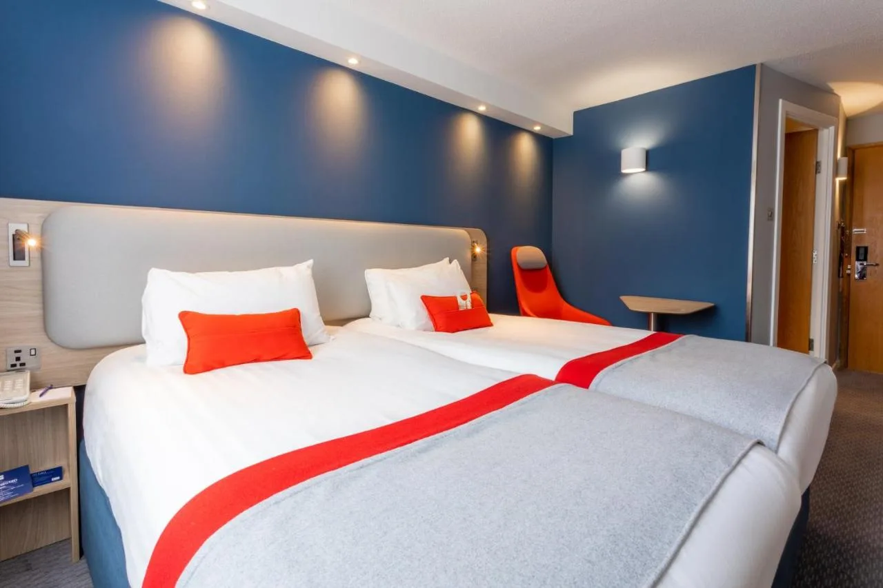 a bedroom with a large white bed with red pillows at Holiday Inn Express Glasgow City Theatreland by IHG in Glasgow